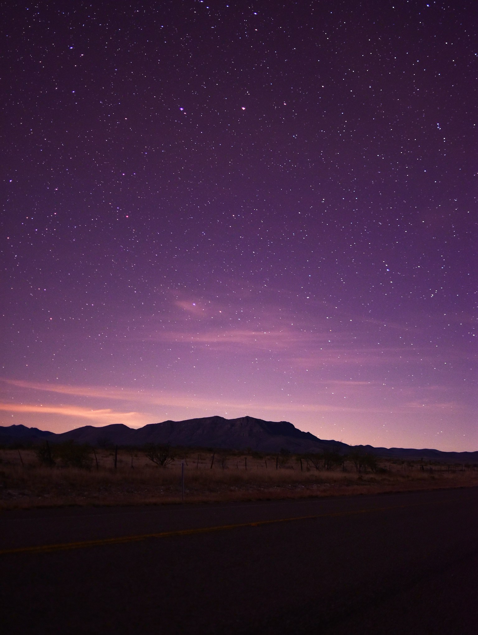 Twilight sky over a dark road beneath bright evening stars