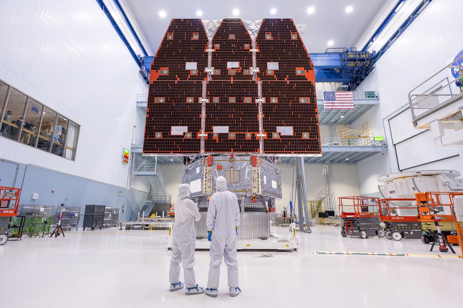 NASA’s Nancy Grace Roman Space Telescope in a Kennedy Space Center clean room with technicians below its solar arrays