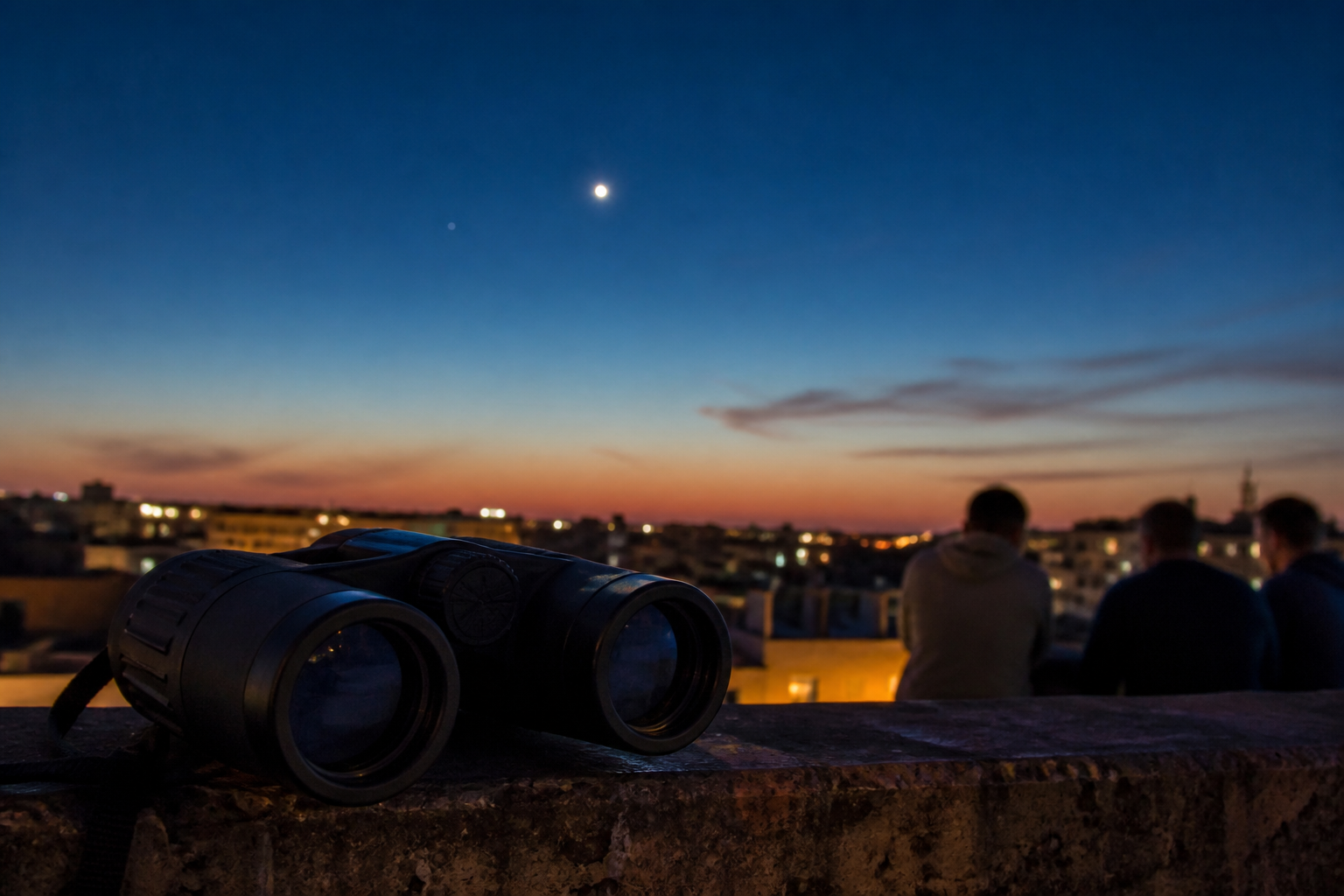 Binoculars wait on a railing beneath a low twilight conjunction.