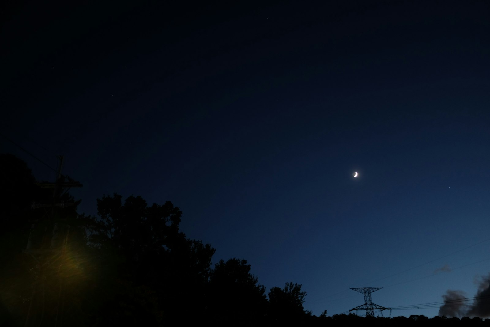 Thin crescent moon with subtle earthshine in a clear twilight sky.