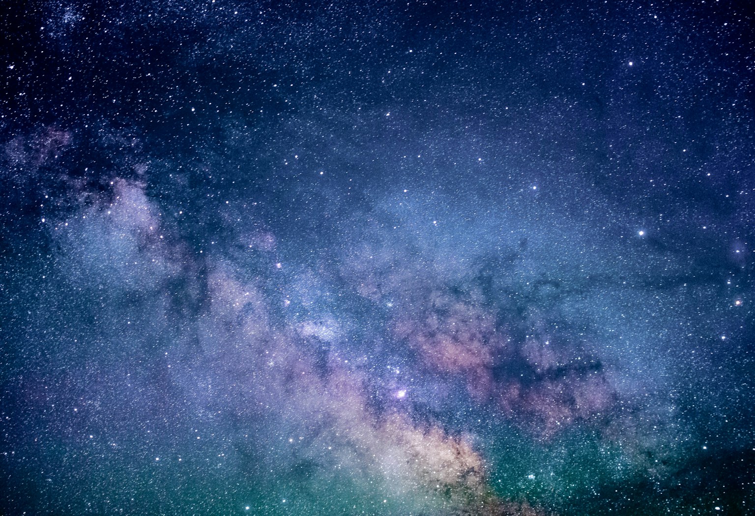A real night-sky landscape with the Milky Way over a dark mountain horizon.