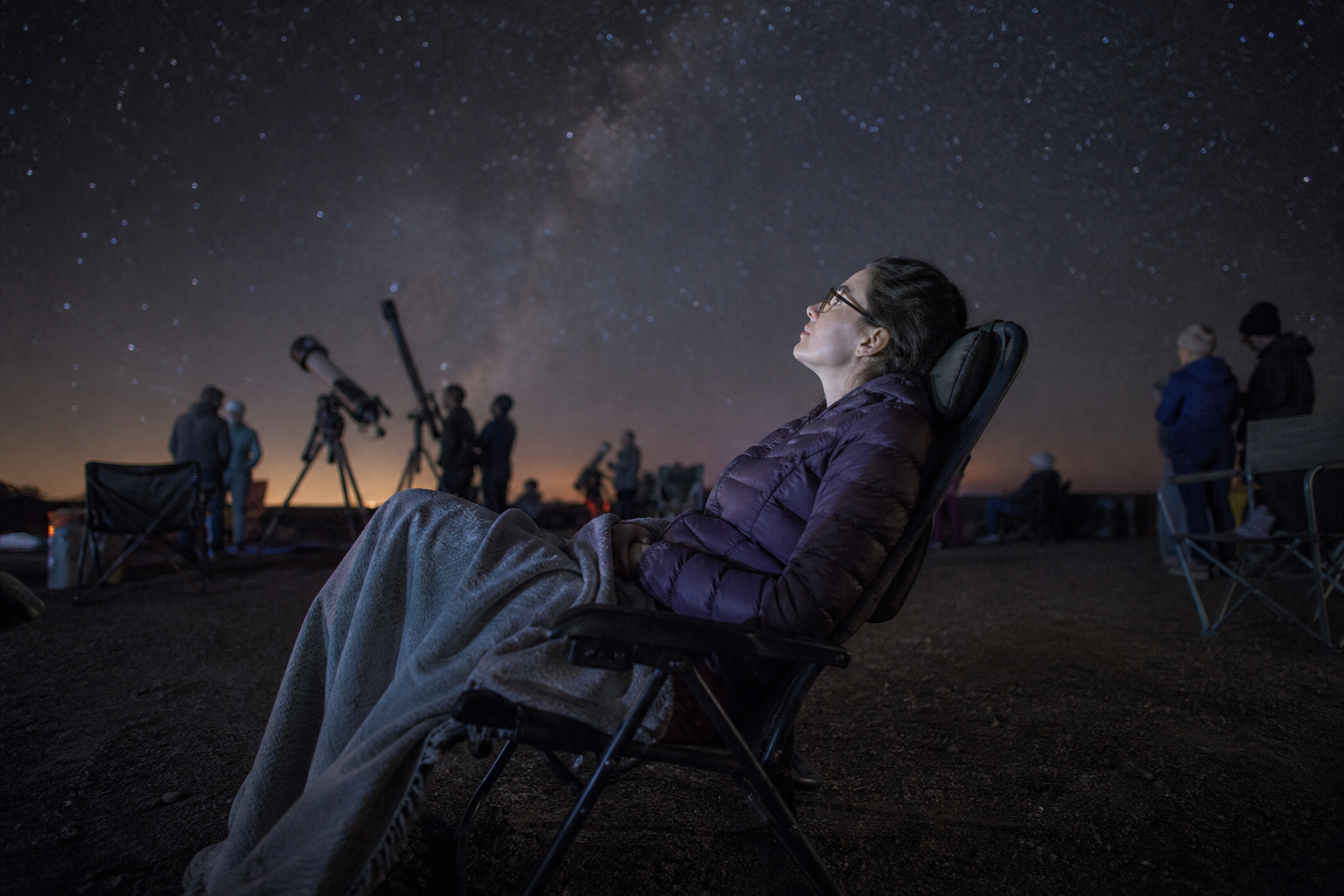 A relaxed observer tests chair comfort during a community astronomy night
