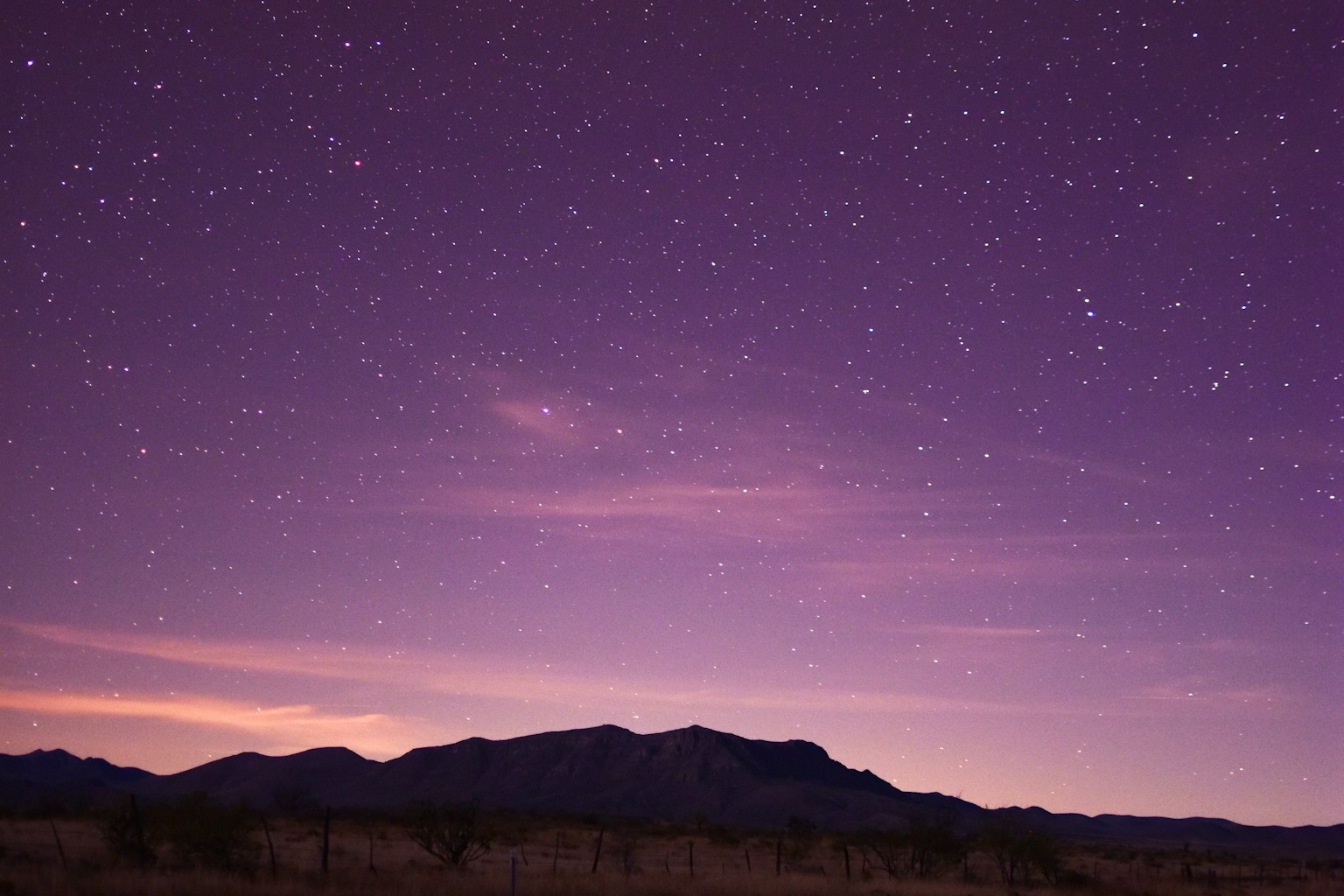West Texas road leading through desert mountains beneath a dense star-filled sky