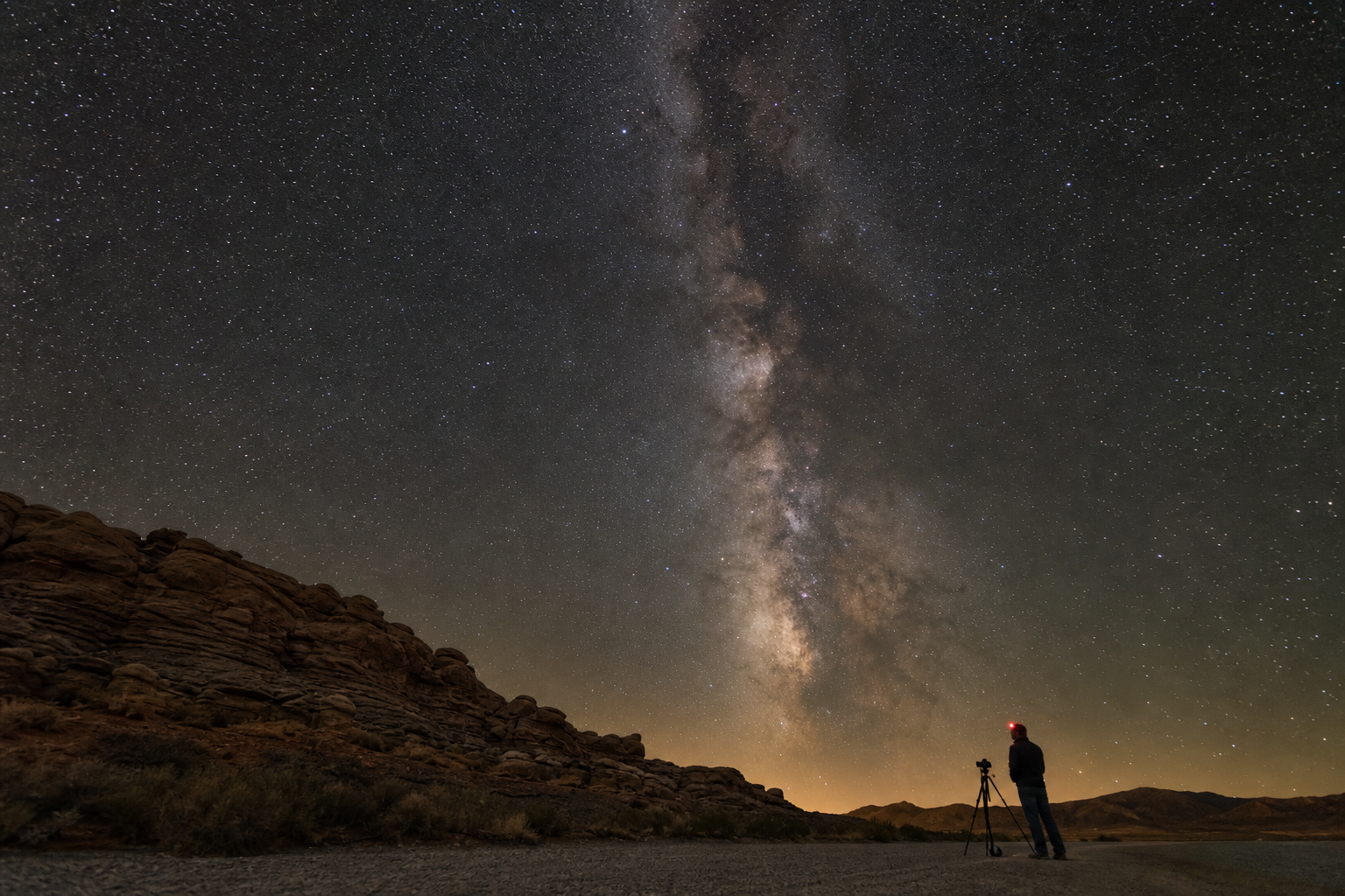 A photographer uses a rocky foreground and tripod to frame the summer Milky Way