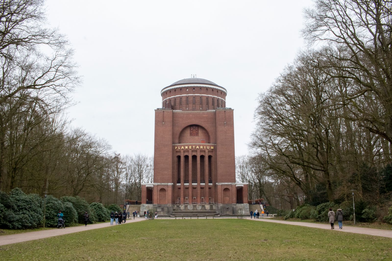 Visitors approach a planetarium building through a park