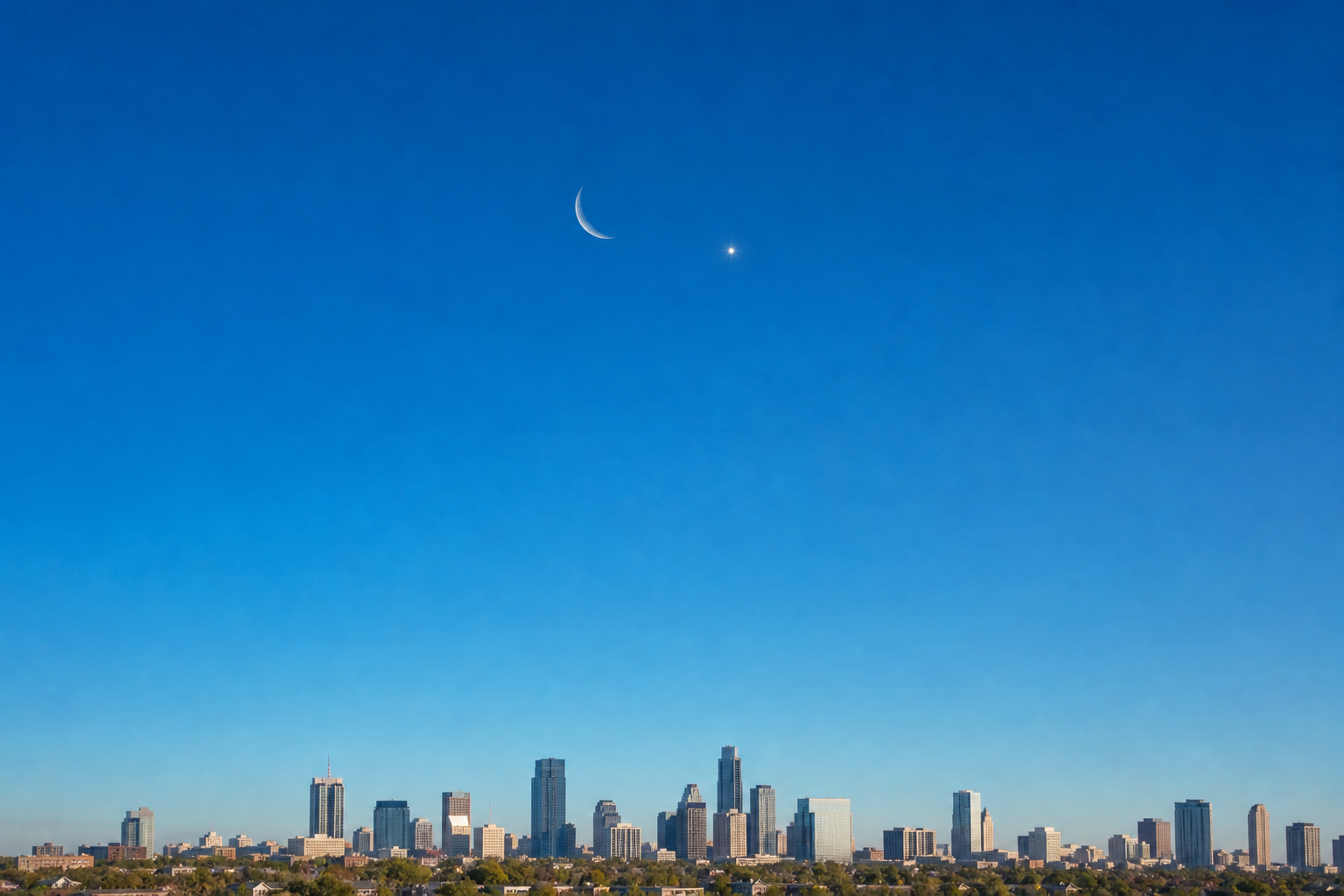 Daylight view of a thin crescent Moon near Venus above a city skyline