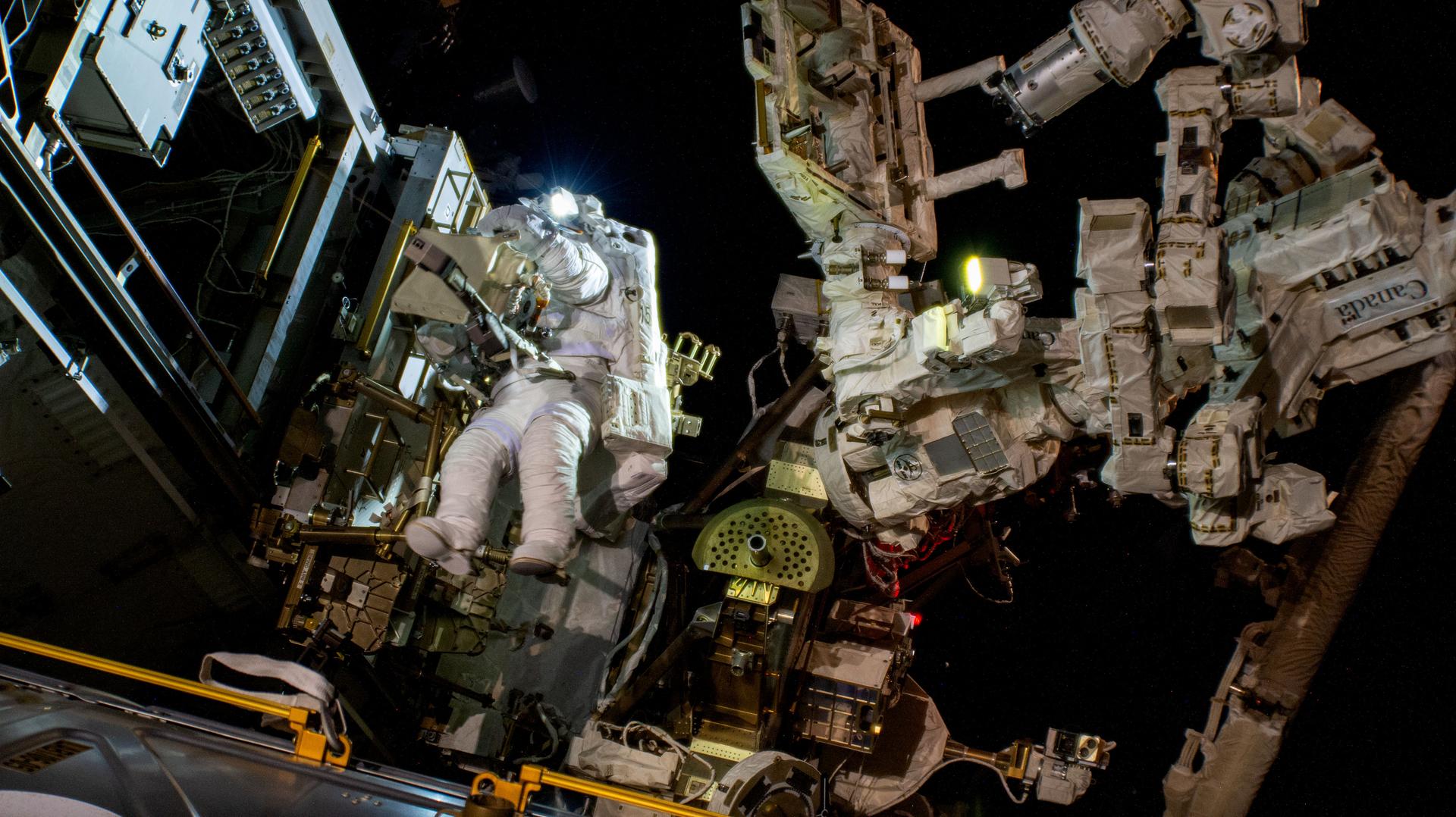 Astronaut conducting a spacewalk outside the International Space Station above Earth, illustrating the completed Spacewalk 98 antenna repair