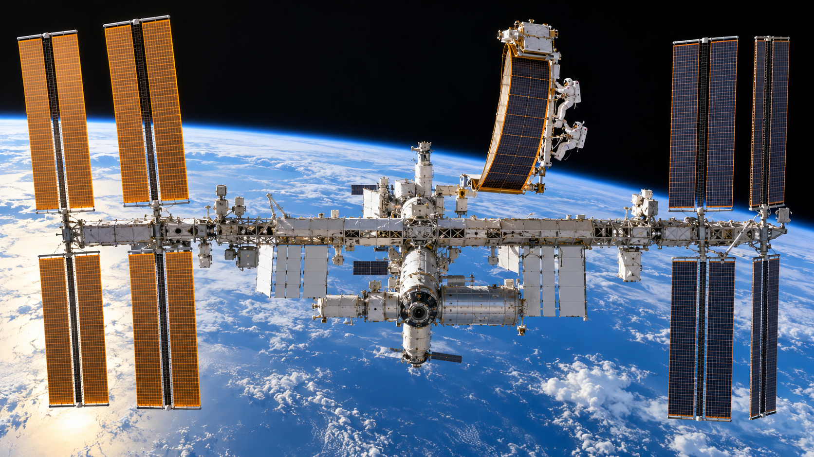 International Space Station with astronauts working near a roll-out solar array