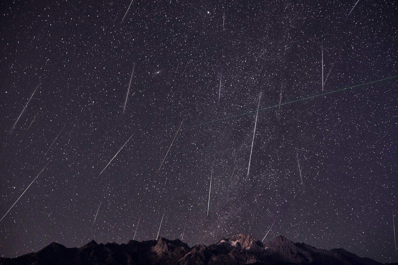Meteor streaks over a dark mountain sky