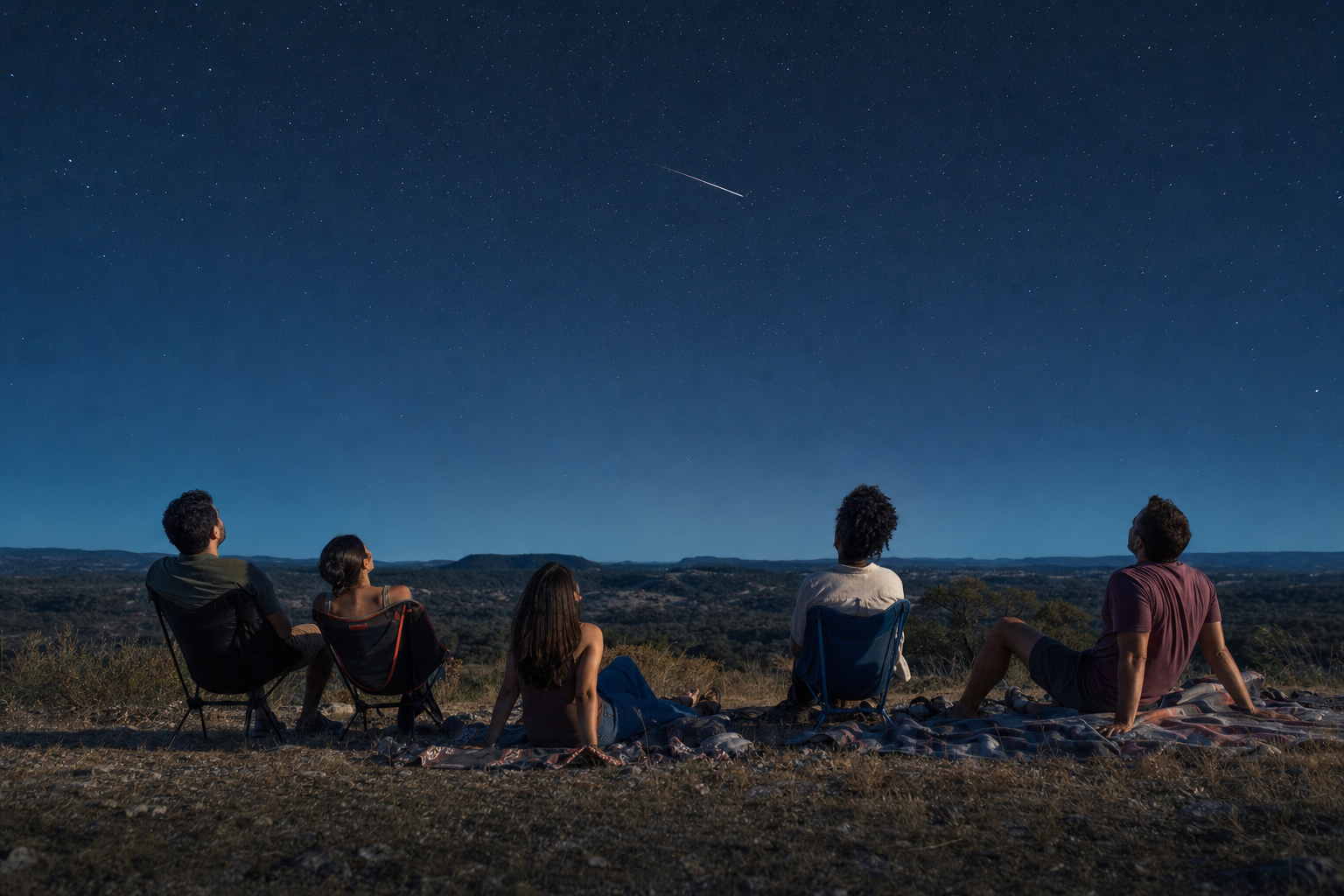 A small group enjoying a calm moonlit meteor watch from a desert overlook