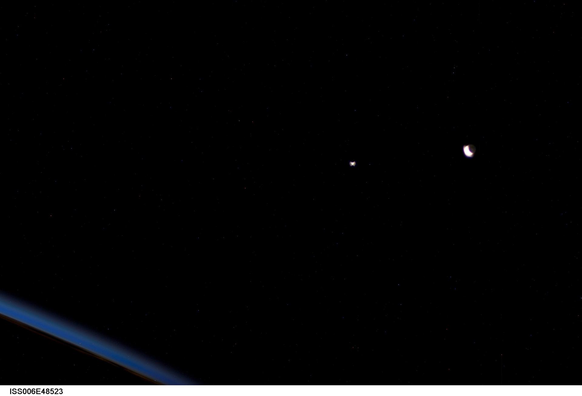 Crescent Moon and Venus glowing above Earth at sunset as seen from orbit