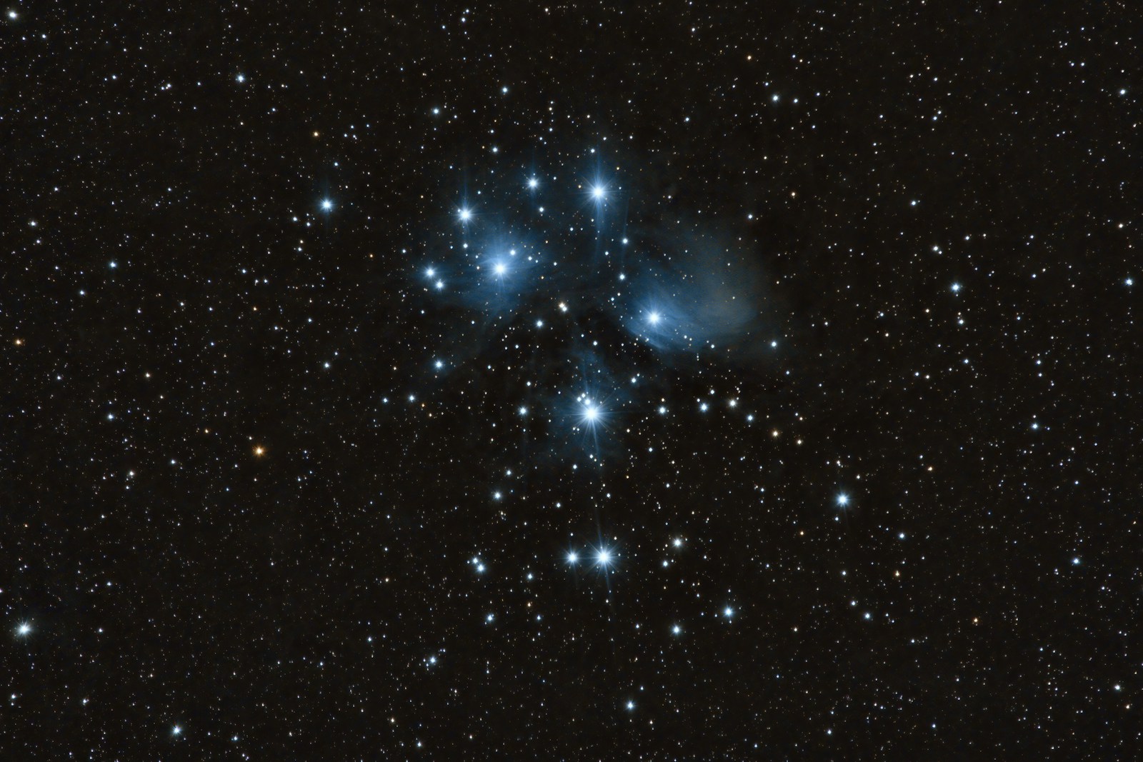 Blue-white Pleiades star cluster glowing against a dark night sky.