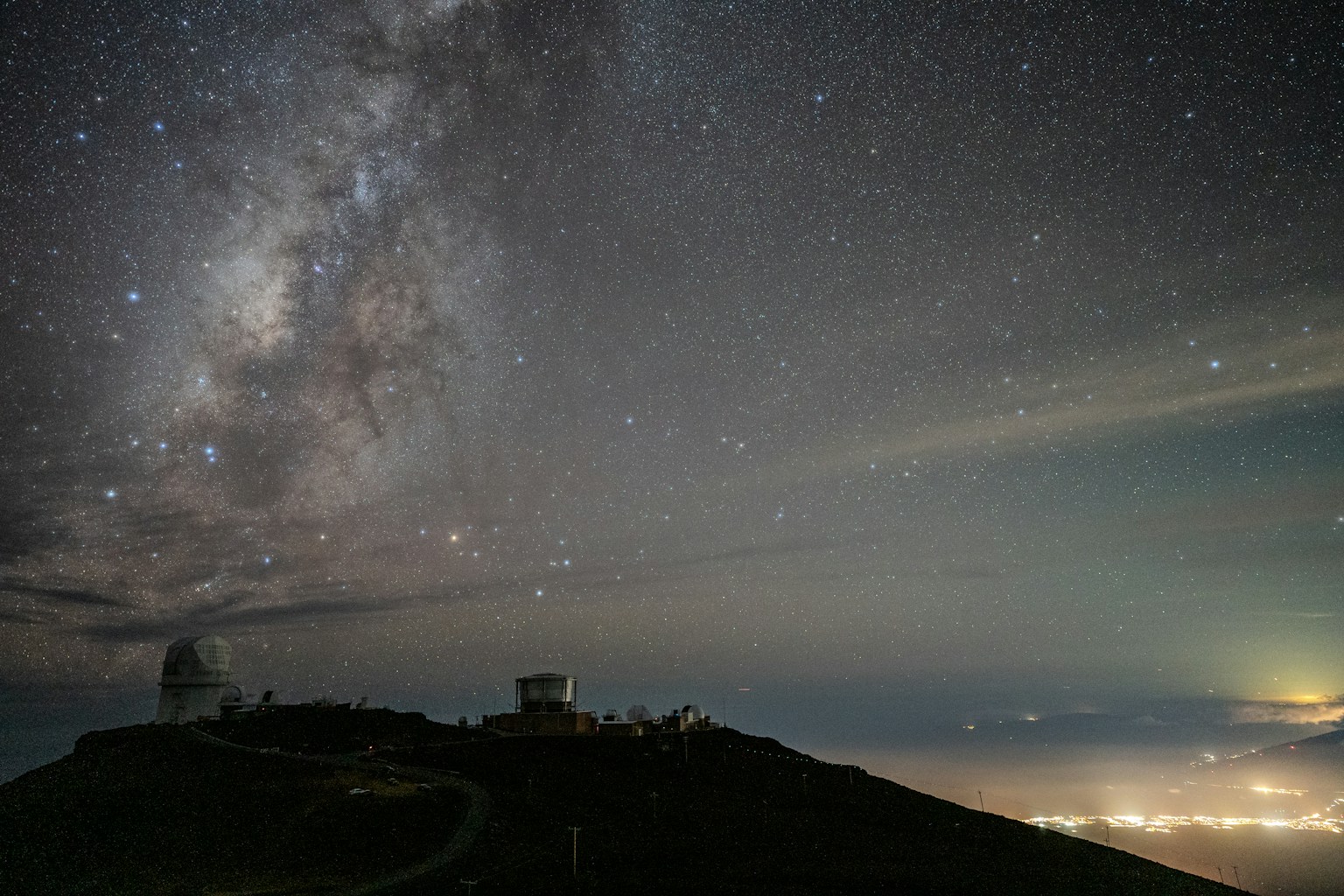 Milky Way above observatory domes at night, photographed at an astronomical observing site.